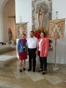 Frau Waltraud Bertossi, Pfarrer Ralf Gössl und Frau Erna Königer (von links) vor den restaurierten Kirchenfahnen.